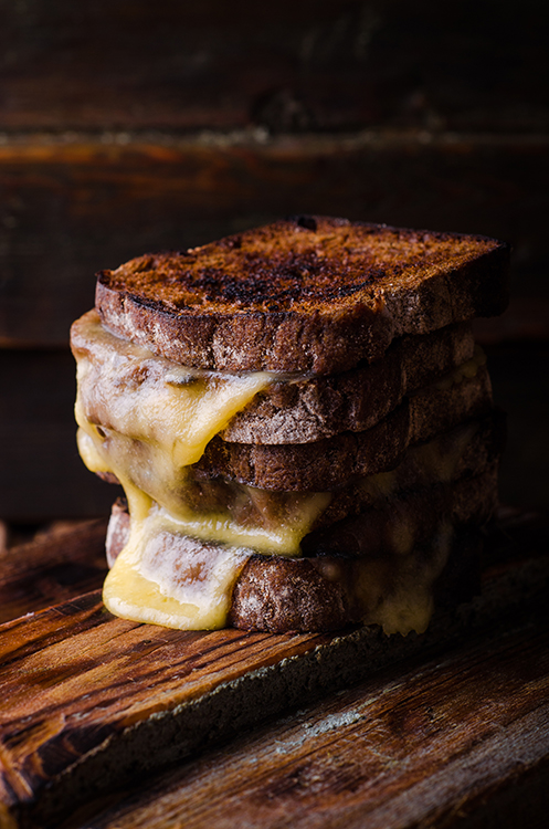 Brown bread toasts with grilled cheese on dark wooden background