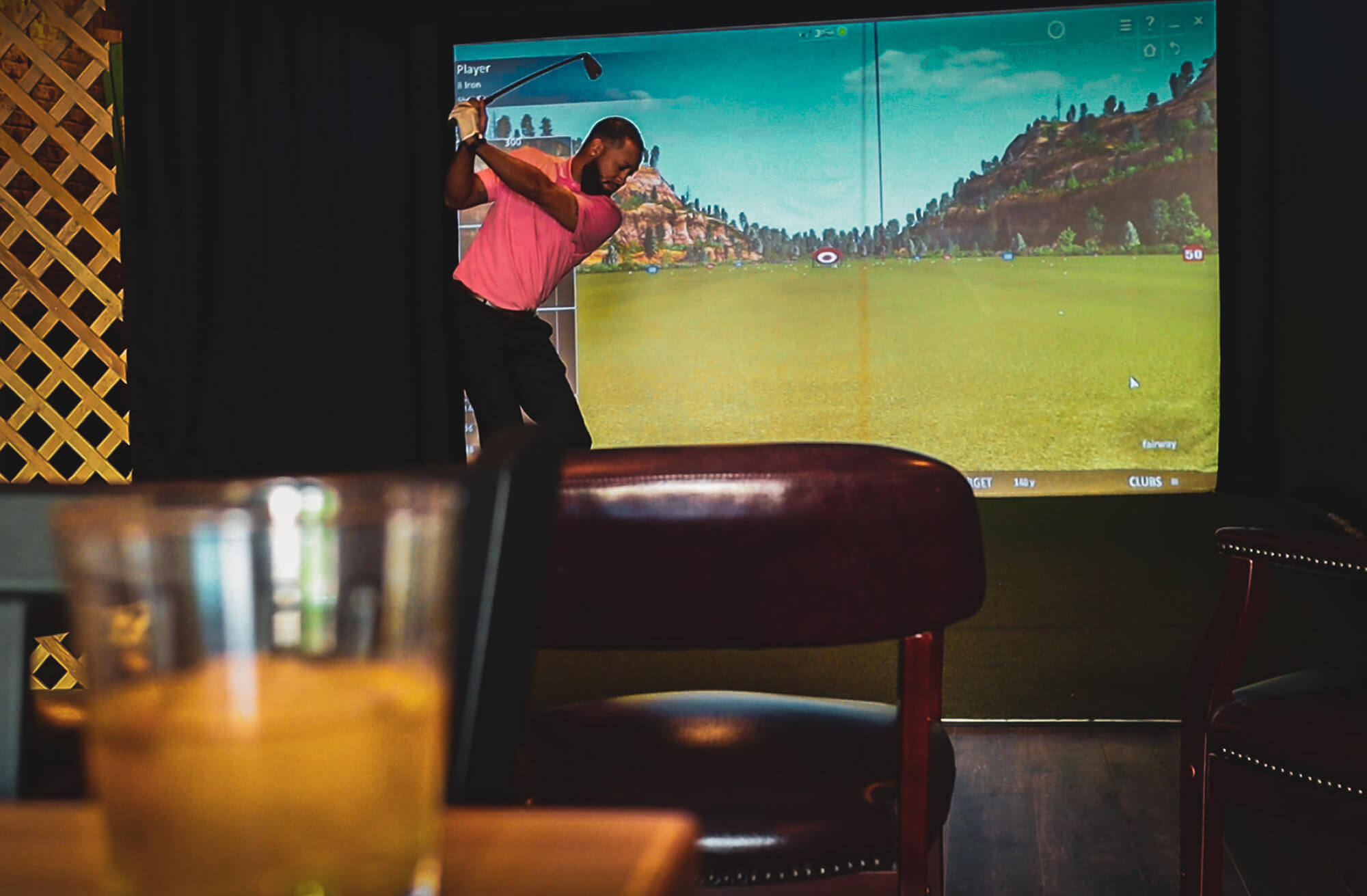 Caddy Shack Golf Pub soft focus on drink with pulled focus on patron using golf simulator Decatur IL