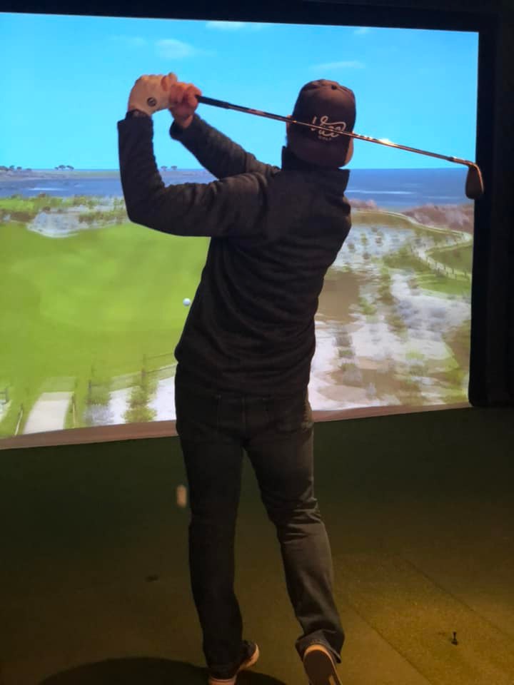 Patron in mid swing using golf simulator Caddy Shack Golf Pub Decatur IL