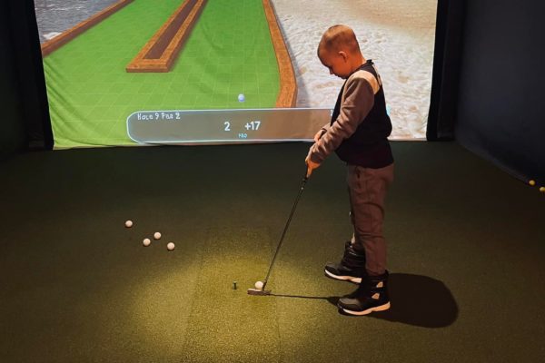 young kid patron enjoying mini golf course on golf simulator Decatur IL